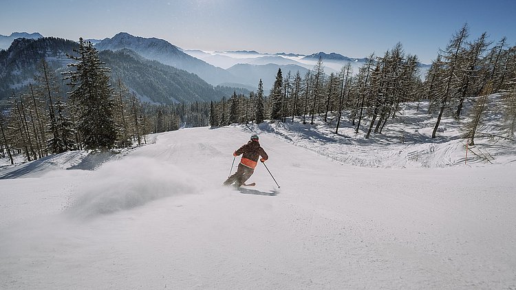 Ein Skifahrer gleitet die Piste auf der Wurzeralm in Spital am Pyhrn ins Tal hinab.