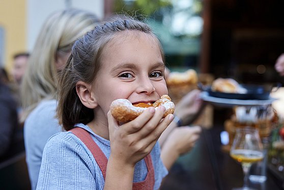 Foto Oberösterreich Tourismus/Innviertel Tourismus/Stefan Mayerhofer: Mädchen isst Bauernkrapfen mit Marillenmarmelade.