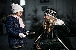Ein Mädchen trifft das Steyrer Christkindl und überreicht ihm seinen Wunschzettel.