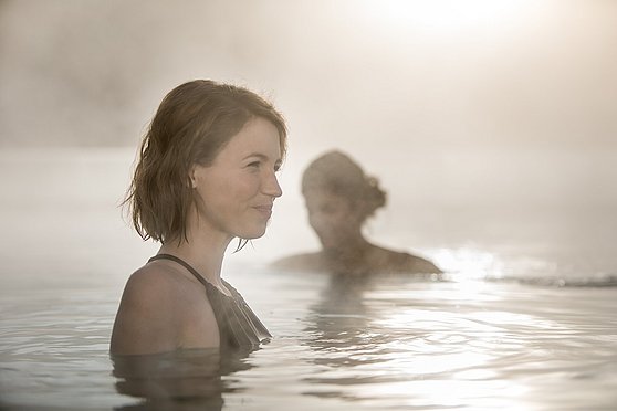 Foto Oberösterreich Tourismus GmbH/Robert Maybach: Zwei Frauen genießen die winterliche Lichtstimmung im Außenpool im Spa Resort Therme Geinberg im Innviertel.