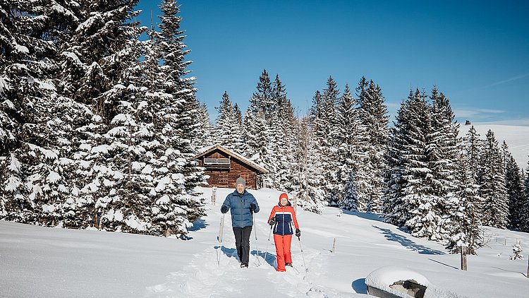 Zwei Wanderer wandern im Schnee auf der Postalm