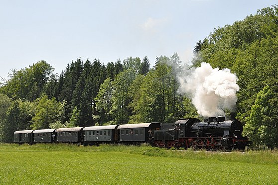 Foto Tourismusverband Hausruckwald/ÖGEG: Museumsdampflok fährt inmitten der grünen Landschaft durch Wiesen und Wälder
