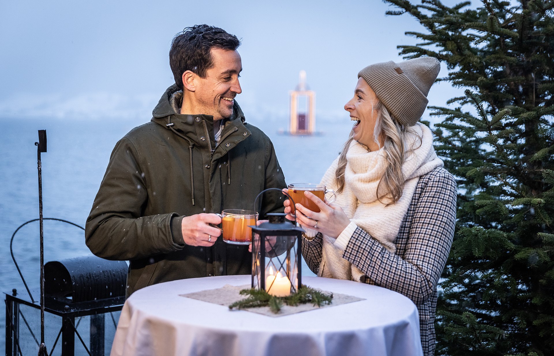 Zwei Liebende, die sich anlächeln und einen Punsch in der Hand halten.