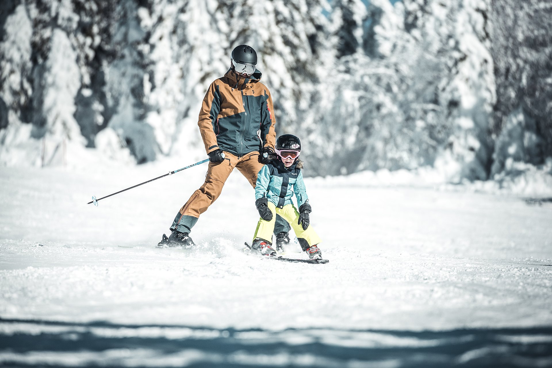 Vater und Kind fahren beim Skifahren lernen im Skigebiet Hochficht am Böhmerwald im Mühlviertel hintereinander im Schneepflug.
